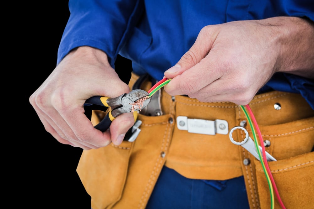 Electrician cutting wires against black